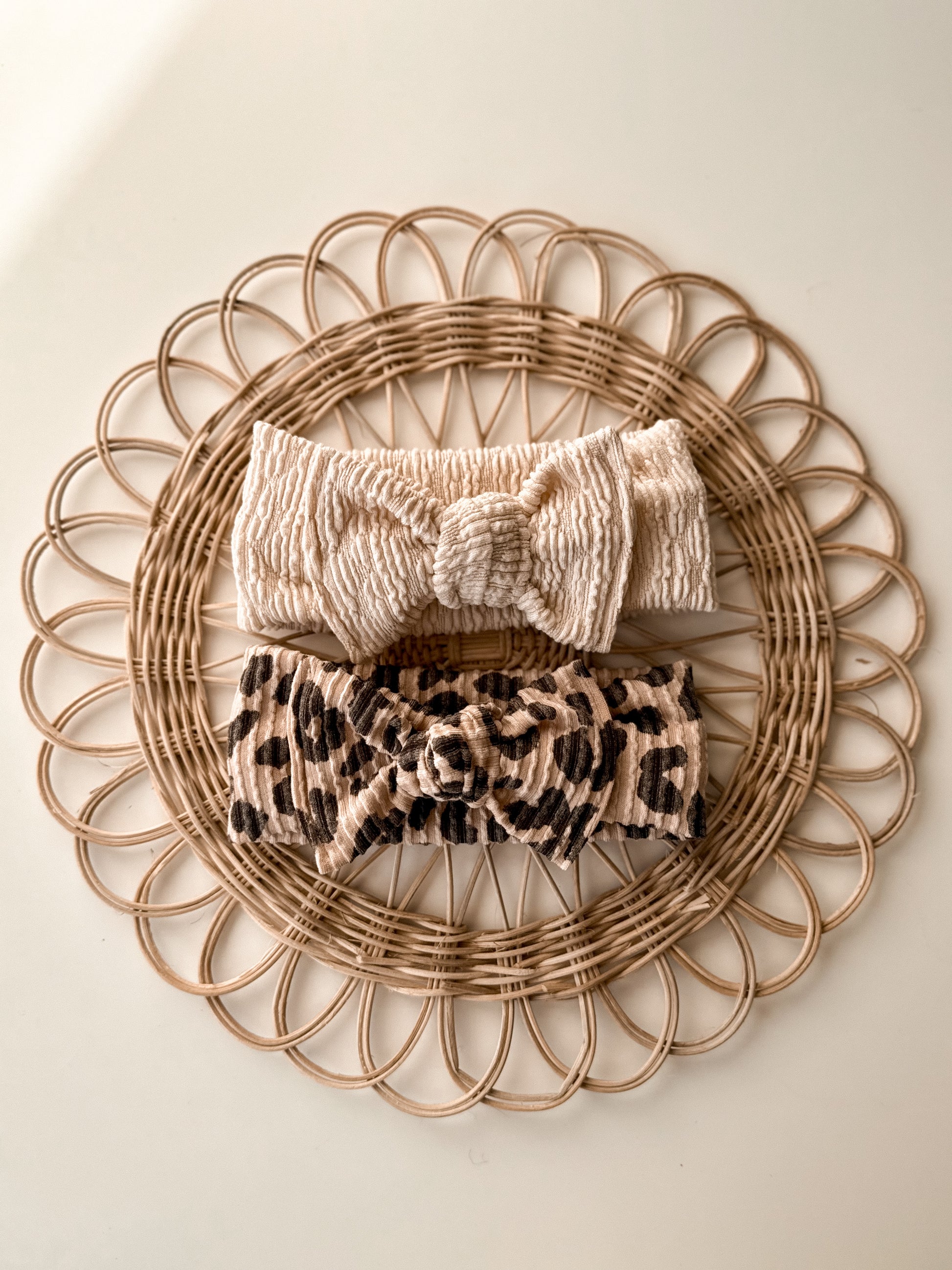 Two headbands, one beige and one leopard print, on a woven basket.